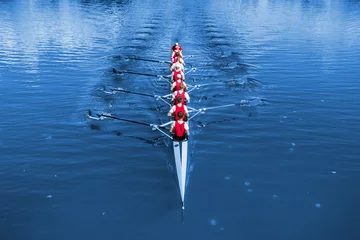 Boot steuerte acht Ruderer, die auf dem blauen See ruderten. Klassische blaue Pantone 2020 Jahresfarbe. © smuki