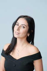Fototapeta premium A large portrait of a middle-aged woman (30-35 years old) with dark hair and brown eyes in a black dress on a light background.