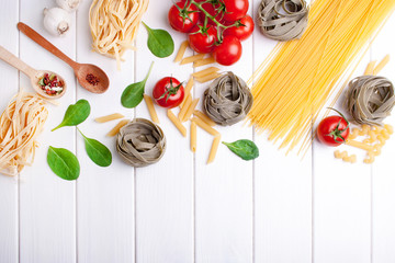 Cooking spaghetti with spinach and cherry tomatoes on a white wooden background. View from above