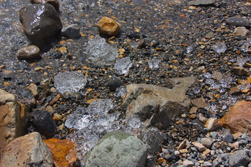 Pieces of ice among stones on the lake shore