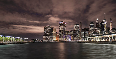 New York Financial District with skyscrapers and the river coast between two old Brooklyn piers before sunrise