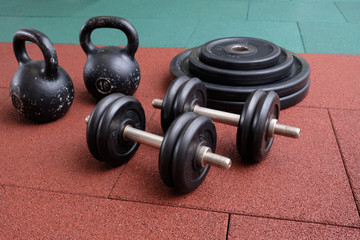 Naklejka na ściany i meble Dumbbells and kettlebells on a floor. Bodybuilding equipment. Fitness or bodybuilding concept background. Photograph taken from above, top view