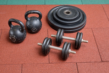 Naklejka na ściany i meble Dumbbells and kettlebells on a floor. Bodybuilding equipment. Fitness or bodybuilding concept background. Photograph taken from above, top view