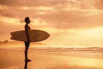 Attractive sporty real surfer at sunset ocean beach
