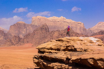 travel life style advertising concept photography of woman stay on top of high rock in the middle of Wadi Rum Jordan desert picturesque landscape environment majestic Middle East nature view