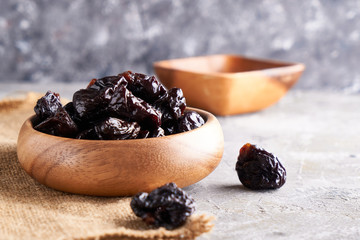 prunes, dried plums in a wooden bowl on a gray background Rustic style