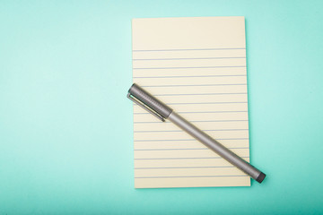 notebook,pen, on turquoise background. top view copy space