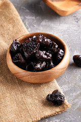 prunes, dried plums in a wooden bowl on a gray background Rustic style
