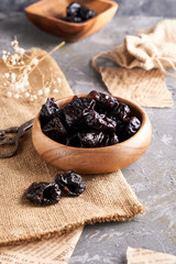 prunes, dried plums in a wooden bowl on a gray background Rustic style