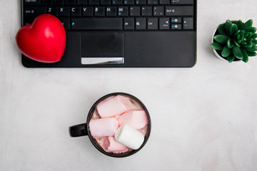 Minimal composition with laptop and mug of cocoa with marshmallows and heart on a white background. symbol of love