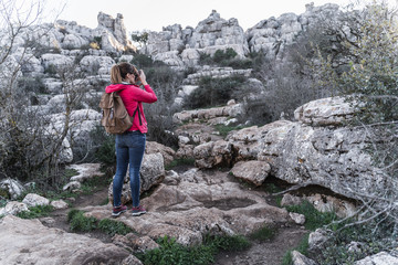 Young woman explorer photographing in the mountain. Concept of adventure, excursion and trips.