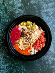 Take Away Jamaican Food Bowl with Chicken, Red Kidney Beans, Beet Sauce, Basmati Rice Pilaf, Avocado Guacamole, Jalapeno Pepper and Coconut Milk in Plastic Container Box / Package.