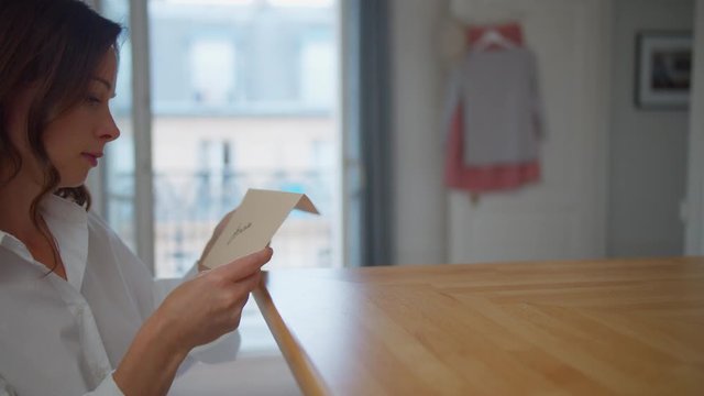 Young woman reading a letter in the apartment in Paris