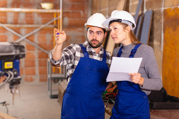 Workers man and woman discuss construction plan