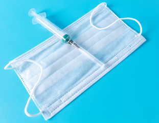 Medical mask and syringe isolated on a blue