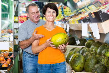 Fototapeta premium Man and his wife are choosing ripe melon