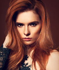 Beautiful passion look young woman with volume red hair style on orange dark studio background....