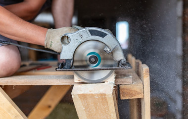 A worker saws a wooden beam.
