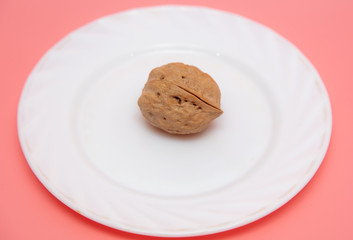 Walnut in a white plate on a pink