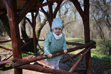  Little girl plays in a wooden gazebo in a spring botanical garden where primroses bloom