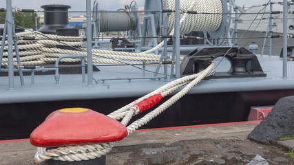 a thick anchor rope holding a ship at the pier as an industrial background