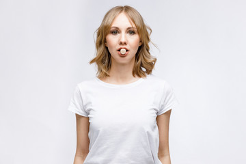 Obraz premium Facial gymnastics. A young girl shows exercises for facial muscles in close-up on a white background.