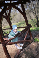 Fototapeta na wymiar Little girl plays in a wooden gazebo in a spring botanical garden where primroses bloom