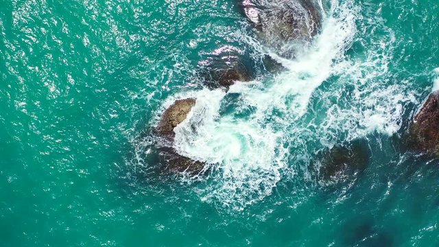 Seychelles rocky coast and rough turquoise sea splashing on the stones. Aerial vertical background