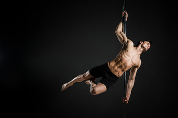 Portrait of male model performing a pole dance - obrazy, fototapety, plakaty