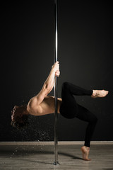 Portrait of professional male model performing a pole dance
