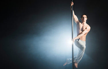 Portrait of attractive male model performing a pole dance