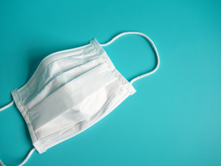close up white surgical face mask on blue green background , the equipment mask to protect man...