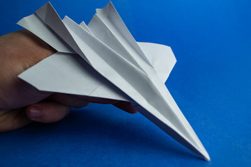  Hand holds paper plane on a blue background
