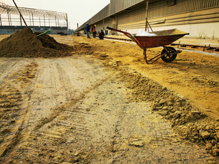 workman is Take a break, Wheelbarrow in construction site is use for pick up sand, area for road asset, Photo is grain film style