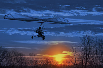 The motorized hang glider fly in the sunset. Classic Blue Pantone 2020 year color.