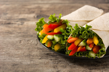 Vegetable tortilla wraps on wooden table. Copy space