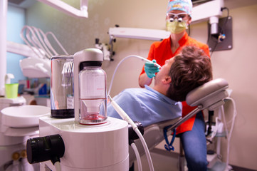 Hygienist removing stains dental plaque and soft deposits on patients teeth with modern non...