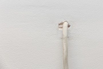 cable wire from a hole in a plastered wall. TV or internet cable wiring