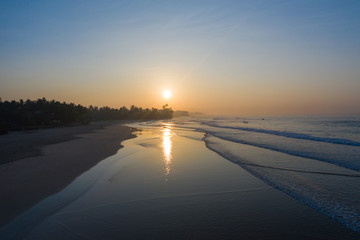 Aerial view of the beach and surfers on the island of Sri Lanka during sunrise