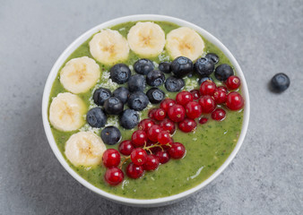 Breakfast detox green smoothie from kiwi, banana, spinach, red currant and blueberries in the bowl.