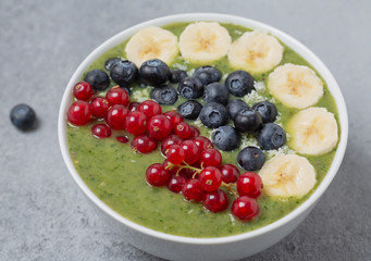Breakfast detox green smoothie from kiwi, banana, spinach, red currant and blueberries in the bowl.