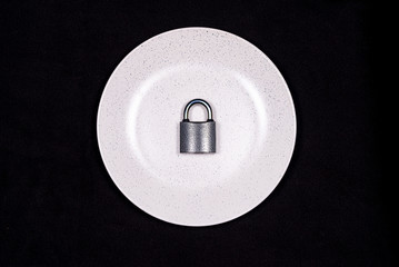 The lock on the plate as a symbol of food restriction in the fight against obesity and gluttony