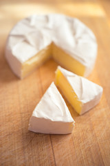 Camembert cheese with two triangles slices on a wooden board