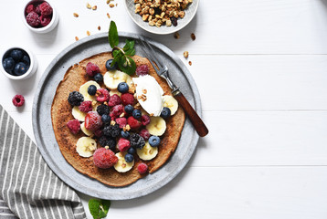 Crepe with berries and yogurt for breakfast. Breakfast on the kitchen table top view.