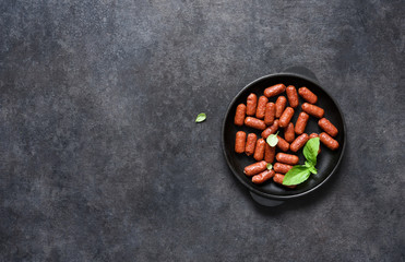 Spicy chorizo sausages in a cast-iron pan on a black background with place for text.