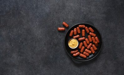 Spicy chorizo sausages in a cast-iron pan on a black background with place for text.