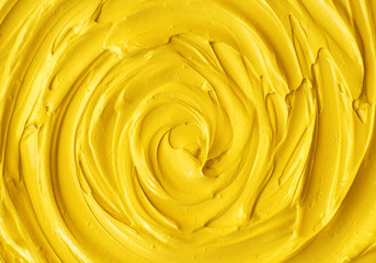 Yellow cosmetic facial mask (cream, body scrub) texture close up, selective focus. Abstract background with circle brush strokes.