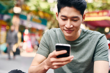 Young Vietnamese man using mobile phone in the city