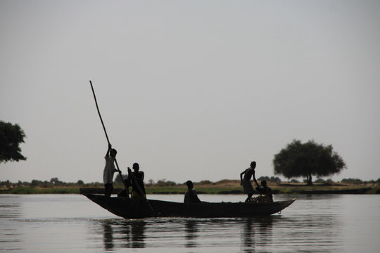 czarni meżczyźni w czółnie płynący po rzece niger w mali