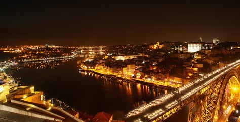 Fototapeta na wymiar Vista nocturna de la desembocadura del río Douro a su paso por las ciudades de Oporto y Vila Nova de Gaia en Portugal y del famoso puente Don Luis I que las comunica.